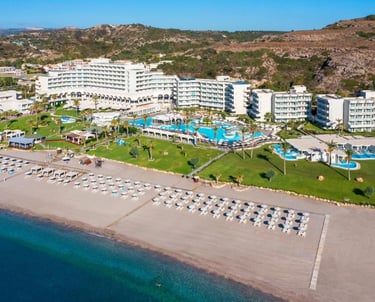 Aerial view of a luxury beachfront resort with swimming pools, white umbrellas, and turquoise ocean water.