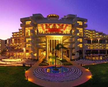 Luxury five-star beach resort hotel illuminated at sunset with modern architecture and gardens.