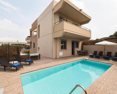 Modern luxury villa with a private swimming pool, sun loungers, and outdoor patio furniture.