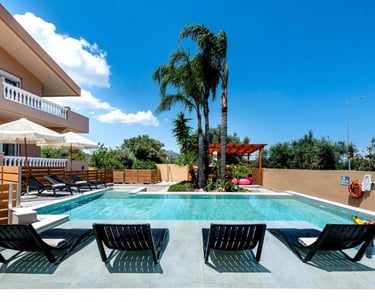 Luxury villa rental with a private swimming pool, sun loungers, and palm trees under a blue sky.