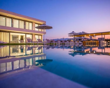 Luxury modern villa with an outdoor infinity pool and lounge chairs at sunset.