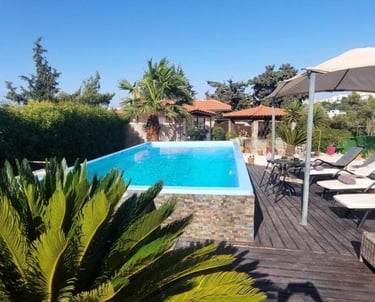 Luxury outdoor swimming pool with sun loungers and umbrella on a wooden deck.