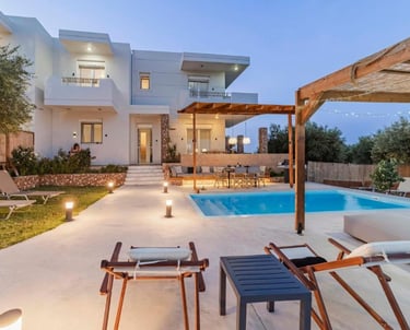 Luxury modern villa with a private swimming pool, outdoor lounge area, and patio at twilight.