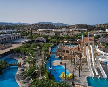 Aerial view of a family resort water park with white slides, swimming pools, and rope course.