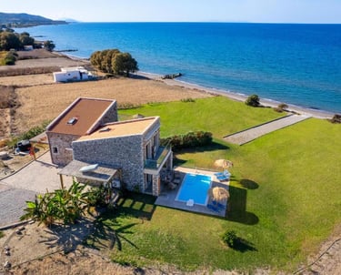 Luxury stone beachfront villa with private swimming pool and green lawn overlooking the blue Mediterranean sea.