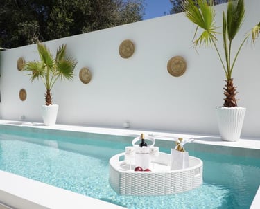 Luxury white swimming pool with a floating champagne breakfast tray and palm trees.