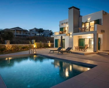 Luxury modern villa at dusk with an illuminated private pool and outdoor patio lounge.