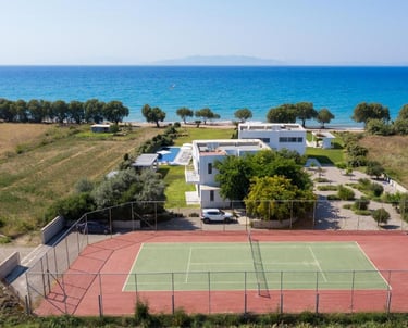 Luxury beachfront villa with a private tennis court and swimming pool overlooking the blue sea.