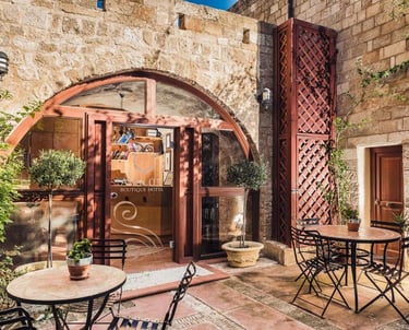 Rustic stone courtyard at Avalon Boutique Hotel featuring outdoor seating and arched glass entryway.