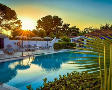 Luxury hotel swimming pool with lounge chairs and umbrellas during a vibrant golden hour sunset.