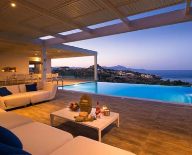 Luxury villa patio with infinity pool, lounge seating, and sunset ocean views.
