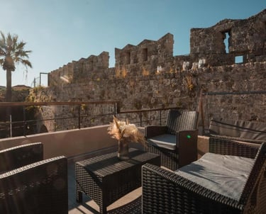 Luxury patio furniture on a rooftop terrace overlooking the historic stone walls of Rhodes Old Town.
