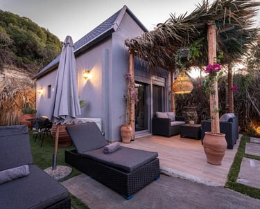 Luxury vacation cottage with a tropical patio, wicker lounge chairs, and a thatched pergola.