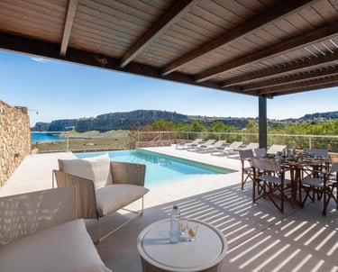 Luxury villa terrace with private pool, outdoor dining set, and scenic ocean views in Greece.