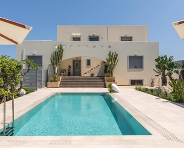 Luxury modern villa with a turquoise swimming pool, sun loungers, and desert landscaping under a clear blue sky.