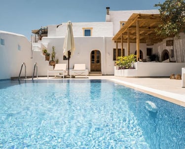 Luxury Greek villa with a private turquoise swimming pool, lounge chairs, and Cycladic architecture.