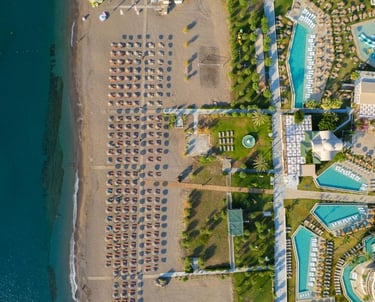 Aerial view of a luxury beachfront resort with swimming pools and sand beach umbrellas.