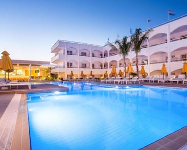 Luxury resort swimming pool with lounge chairs and palm trees at dusk.