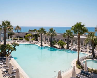 Luxury beach resort with a large swimming pool, palm trees, and ocean view.