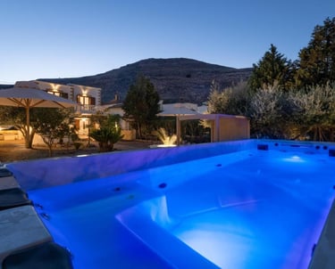 Luxury villa rental with an illuminated blue swimming pool and mountain views at dusk.