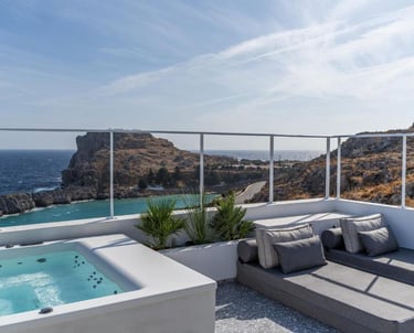 Luxury hotel rooftop terrace with a private hot tub and lounge beds overlooking the Mediterranean Sea.