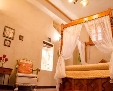 Elegant boutique hotel bedroom featuring a wooden four-poster canopy bed with white lace curtains.