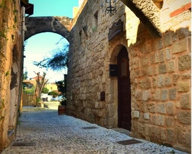 Historic stone alleyway in the Medieval City of Rhodes featuring cobblestone streets and stone arches.
