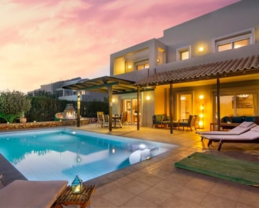 Luxury villa with private swimming pool and outdoor lounge area under a sunset sky.