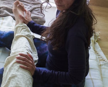 Juliette Maggu in Thai Yoga Massage Position mit Händen am Bein der massiertes Person 