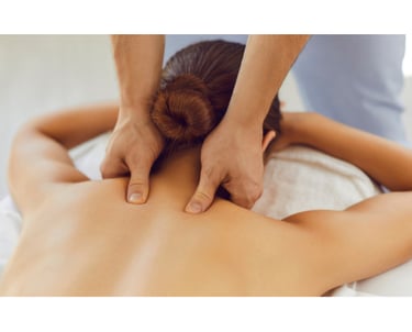 Terapeuta aplicando massagem com os polegares na região cervical de uma paciente deitada em uma maca