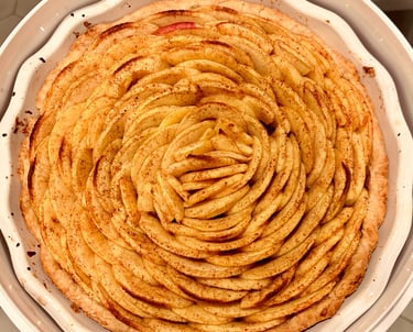 Freshly baked homemade French apple tart with cinnamon-dusted slices arranged in a rose pattern.