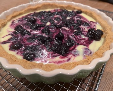 Freshly baked blueberry swirl tart with a buttery short crust in a fluted ceramic dish.