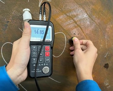 Technician performing ultrasonic thickness testing on an ISO tank using a digital gauge