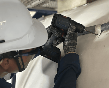 Technician installing external pipe lining on ISO tank during modification work