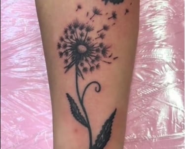 a tattoo of a dandela flower on a woman's forearm