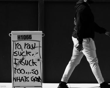 street image of a sign sitting on the sidewalk in brooklyn with a man walking through the frame