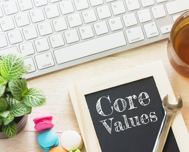 A small chalkboard on a modern work desk reads, "Core Values."