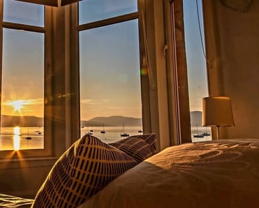 The bed at Gourock Seaview Holiday Let with a view of the sun setting over the water