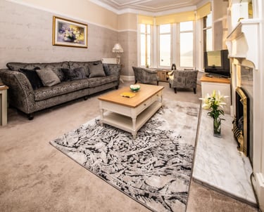 The spacious living room at Gourock Seaview Holiday Let with a couch, armchairs and a fireplace
