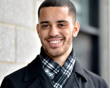 man in a black pea coat and a plaid scarf