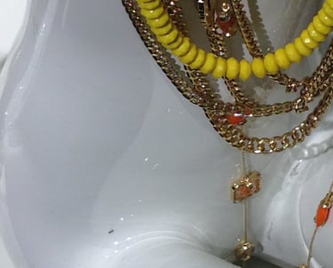 White shiny reflective female manekin with gold chains and blue-yellow plastic neckless.  