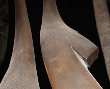 Two sculpture-like brownish long protrusions pointing upwards into a dark space.. 