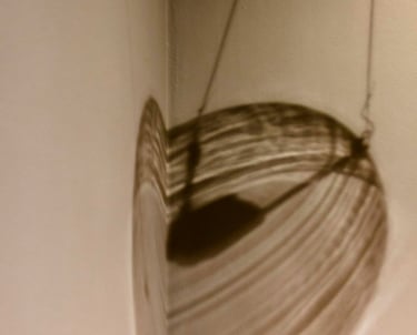 Out of view light fixture casting linear brownish shadows in the corner of the wall.