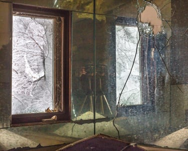 Broken mirrors reflecting a small window with a broken glass.