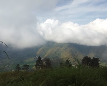 On a mountain top overlooking a valley with clouds hiding the peaks of other mountains
