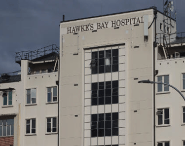 The exterior signage and white facade of Hawke's Bay Hospital building under a cloudy sky.