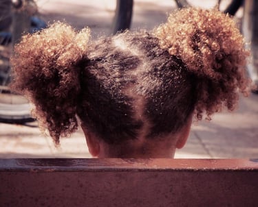 Little mixed race girl with curly hair sitting on a bench