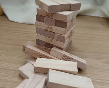 Jenga tower made of wooden blocks on a wooden surface, with several fallen pieces around it.