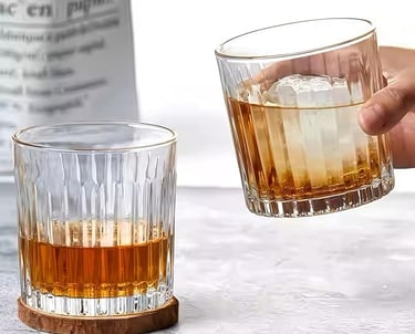 a person holding a glass of alcohol in front of a bottle of alcohol