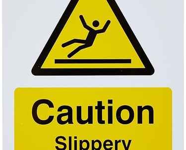 Yellow and black Caution Slippery When Wet safety sign with a falling person icon.
